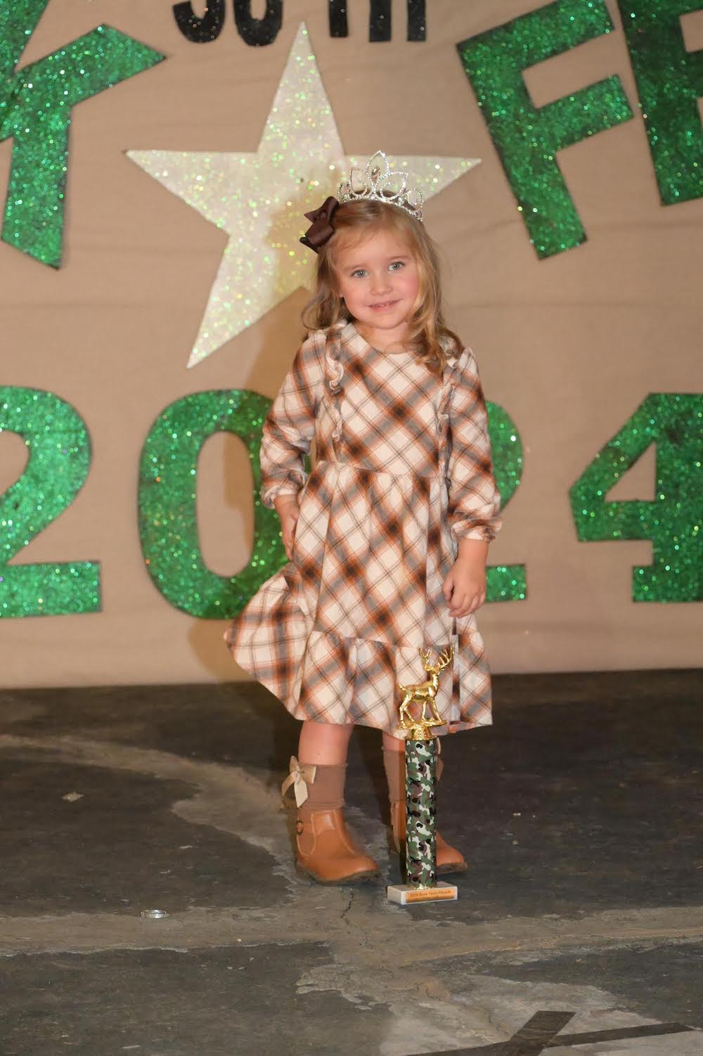 A little girl in cowboy boots and a plaid dress.