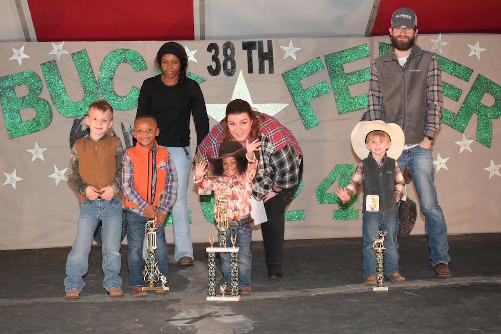 A group of people standing around each other holding trophies.