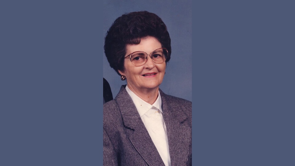 A woman with glasses and a suit on.