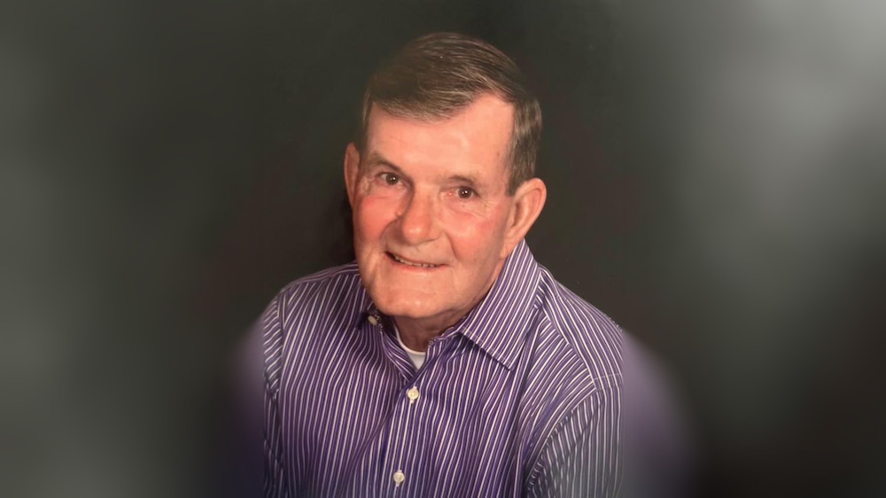 A man in a purple shirt is smiling.