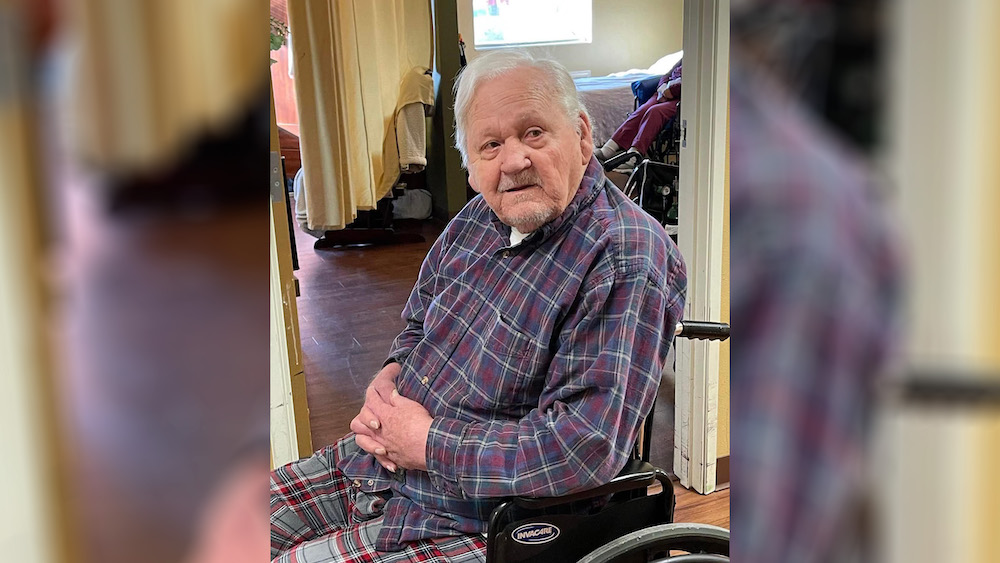 A man in plaid shirt sitting on a wheelchair.
