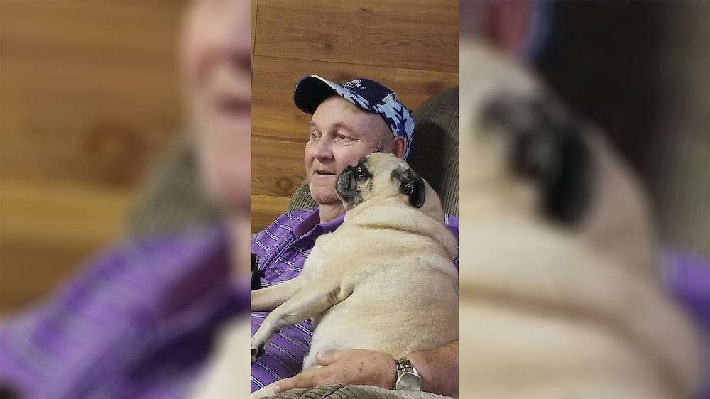 A man holding his dog while sitting on the lap of another person.