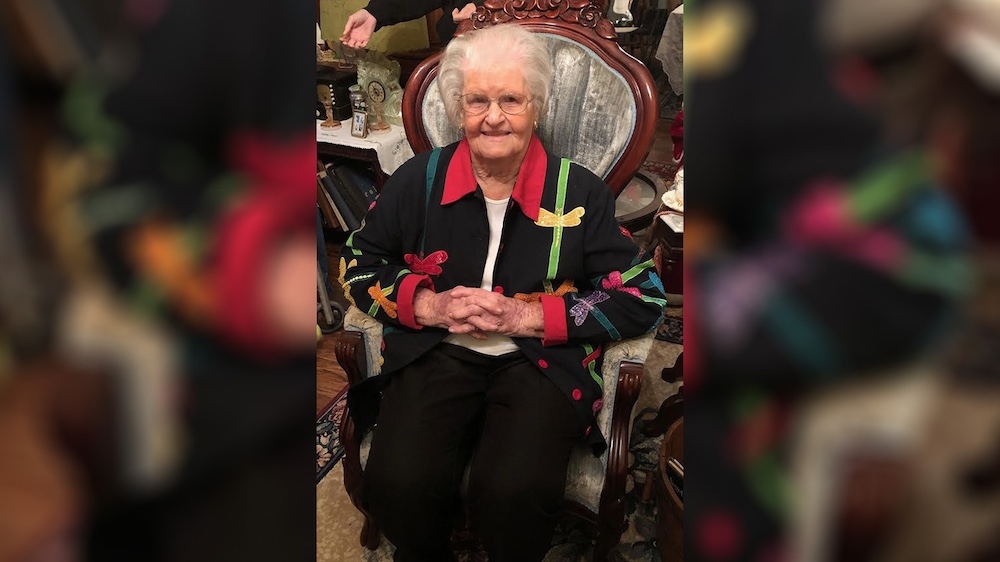 A woman sitting in a chair wearing a colorful jacket.