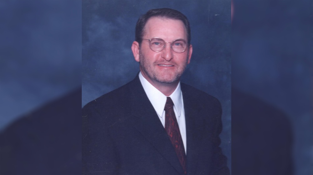A man in suit and tie standing next to a wall.