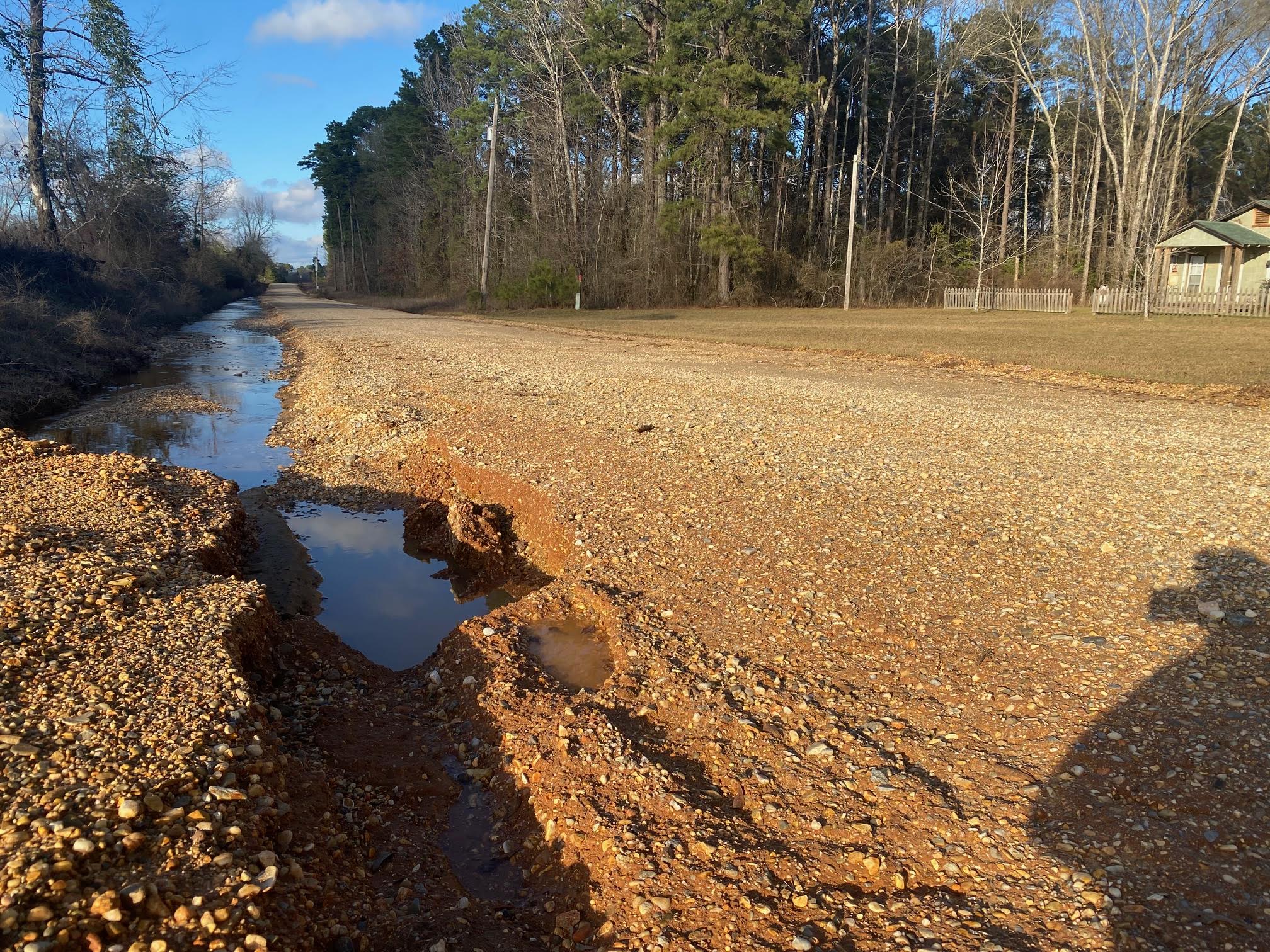 A dirt road with water running down it.