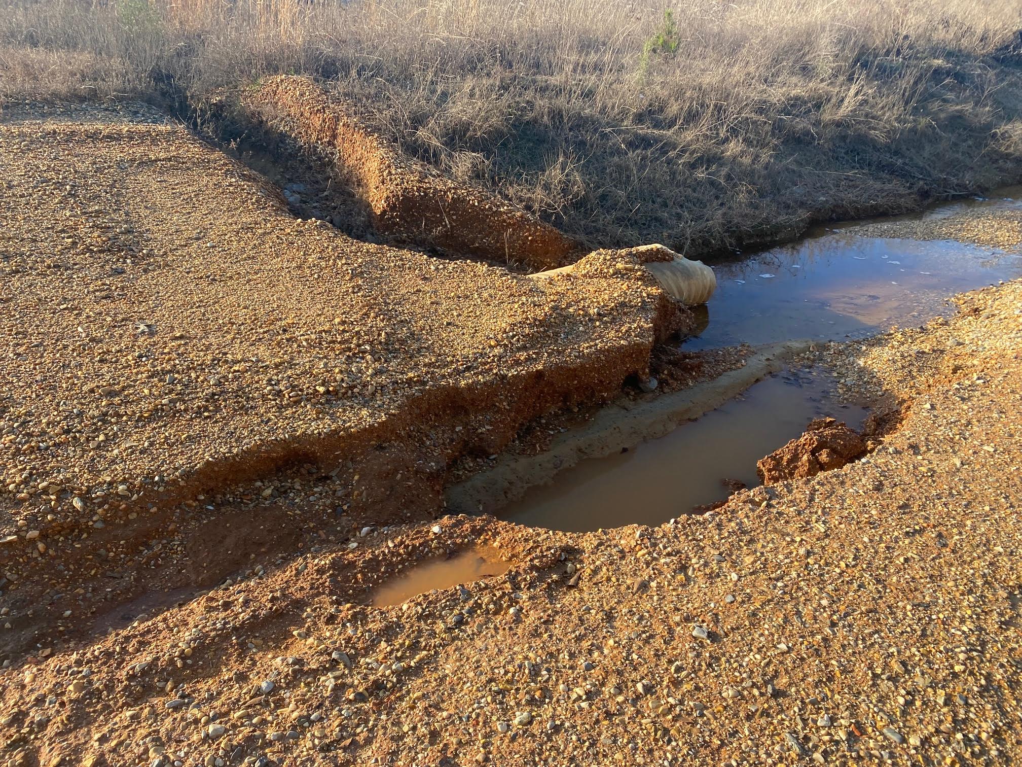 A dirt field with water running down the side of it.