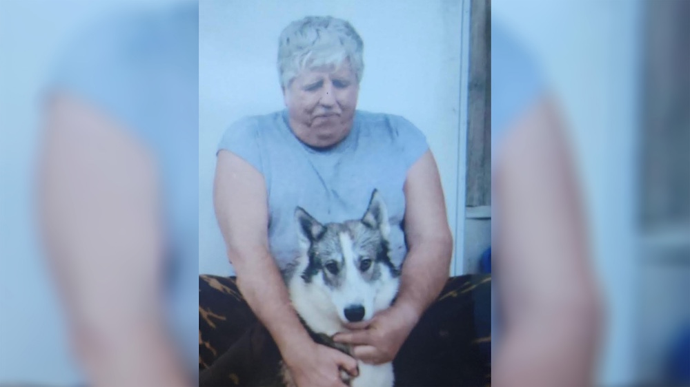 A woman sitting on the ground with her dog.