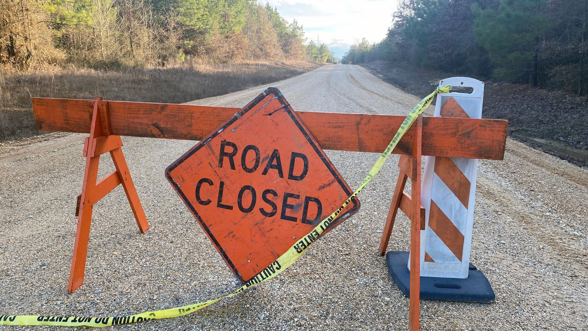 A road closed sign sitting on the side of a road.