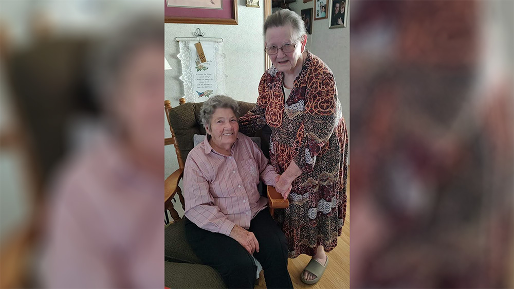Two women sitting in a chair smiling for the camera.