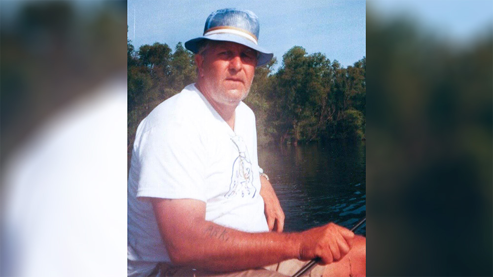 A man in white shirt and hat sitting on boat.