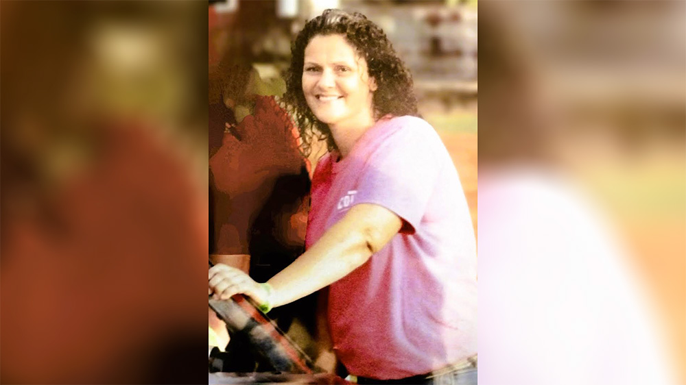 A woman in pink shirt holding a white object.