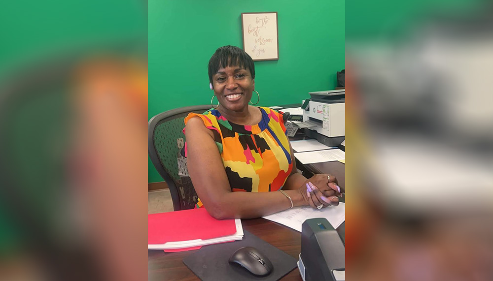 A woman sitting at her desk smiling for the camera.