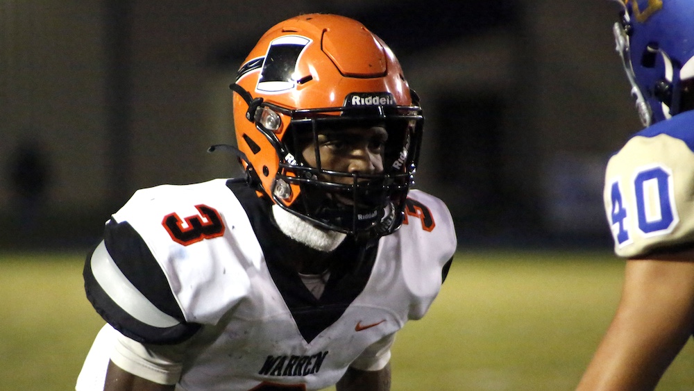 A football player wearing an orange helmet and black uniform.
