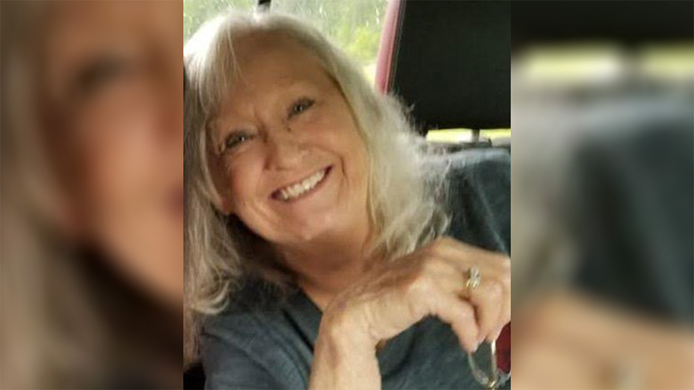 A woman with long white hair smiles for the camera.