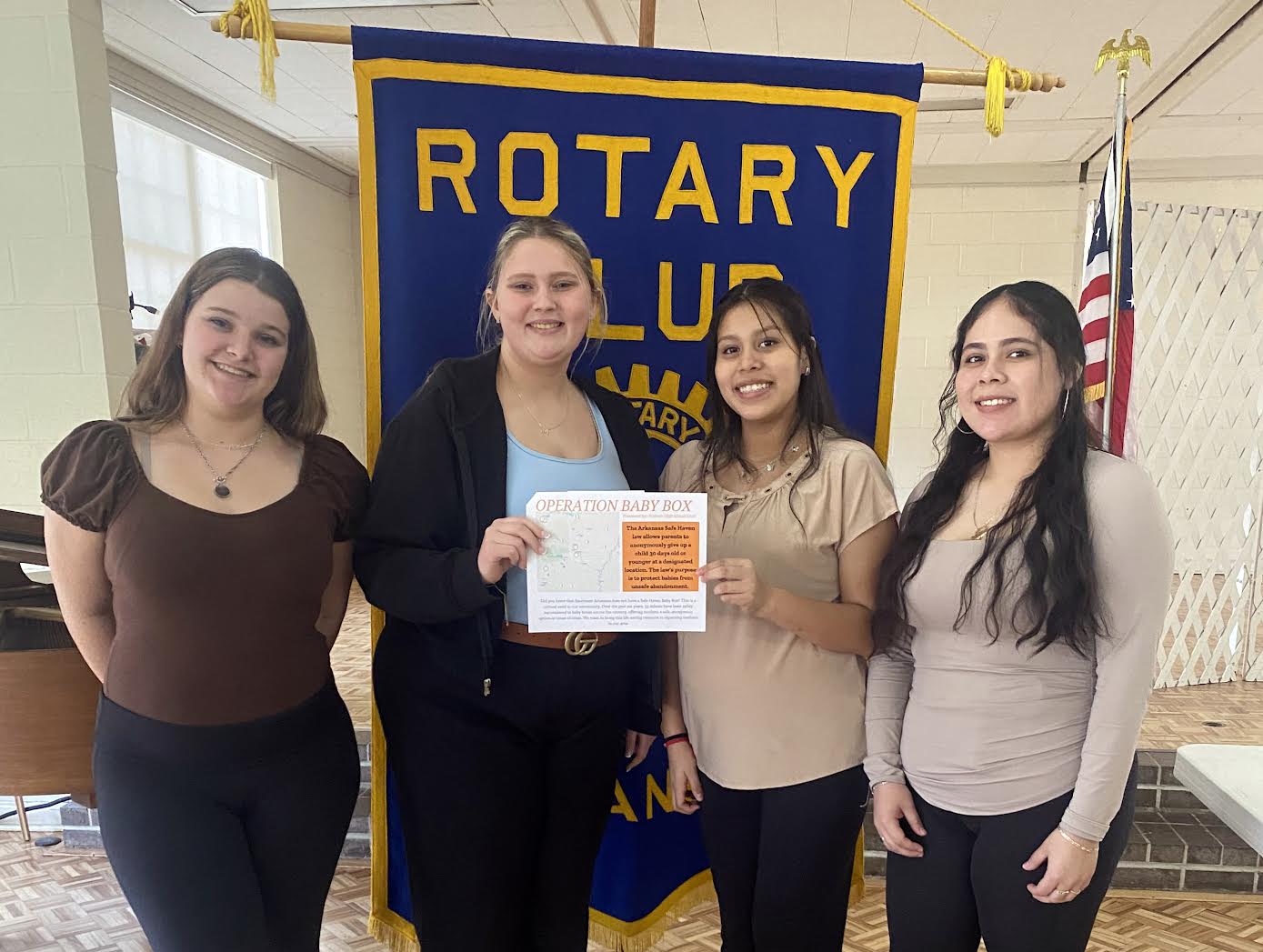 A group of people standing in front of a rotary club banner.