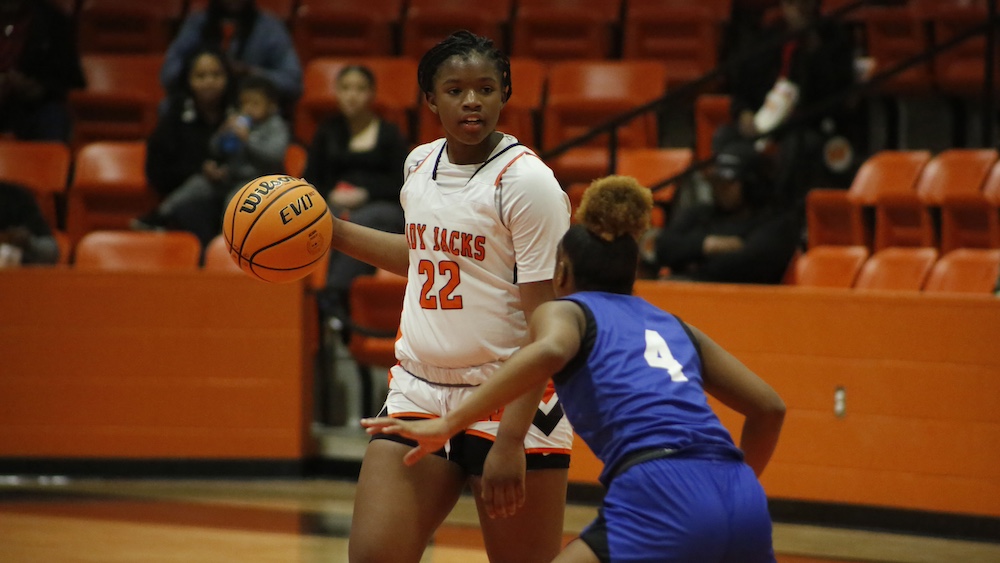 A woman holding onto the ball while playing basketball