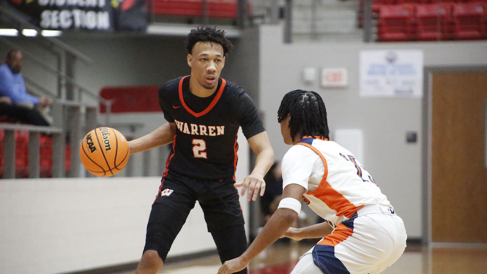 A young man holding a basketball in front of another person.