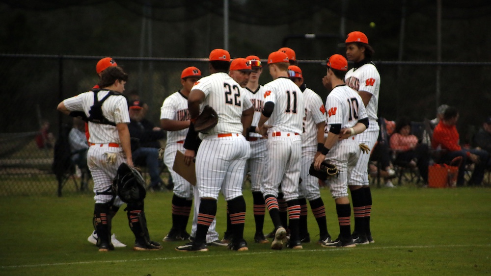 A group of baseball players huddle together on the field.