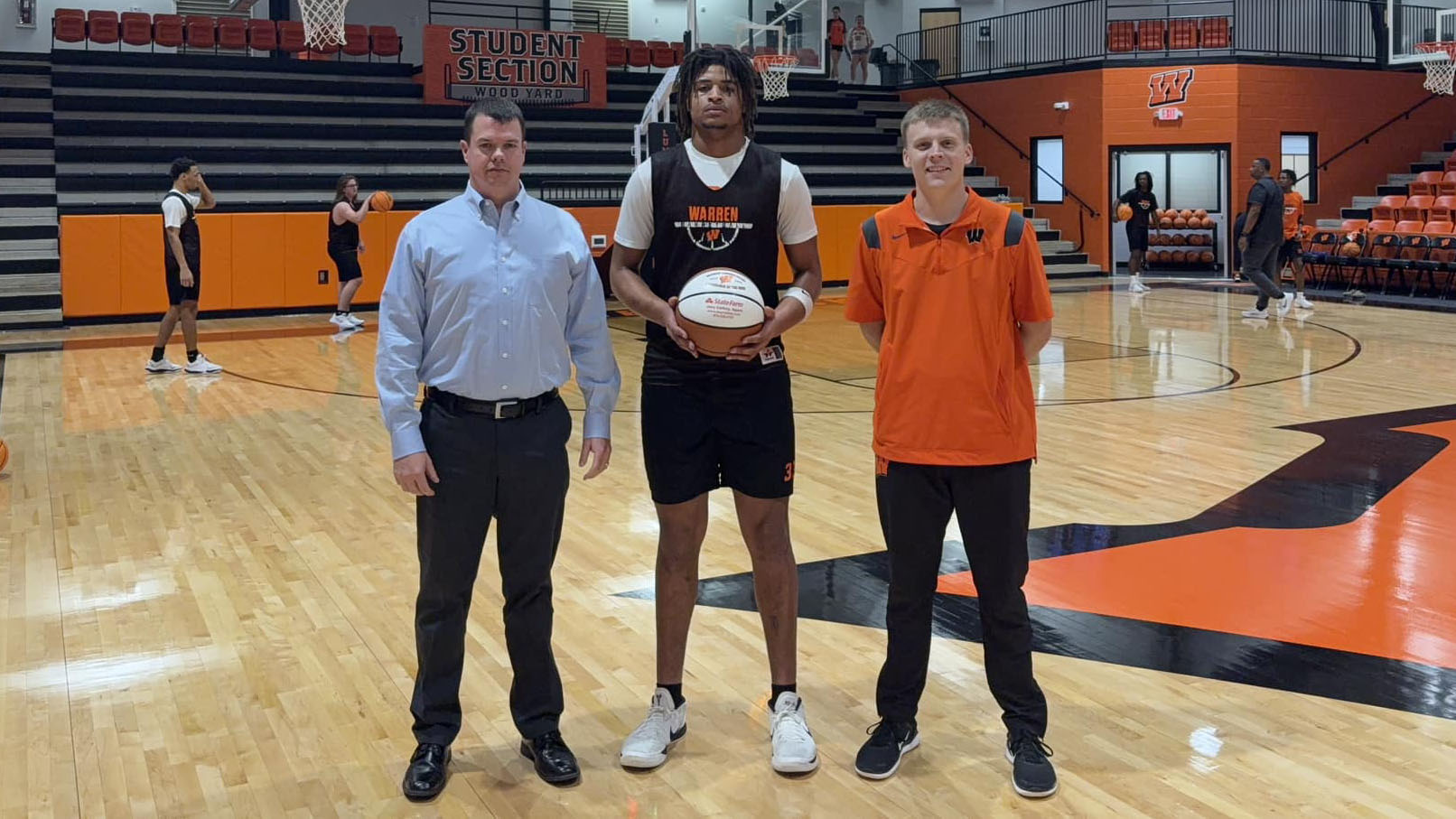 Three men standing on a basketball court holding a ball.
