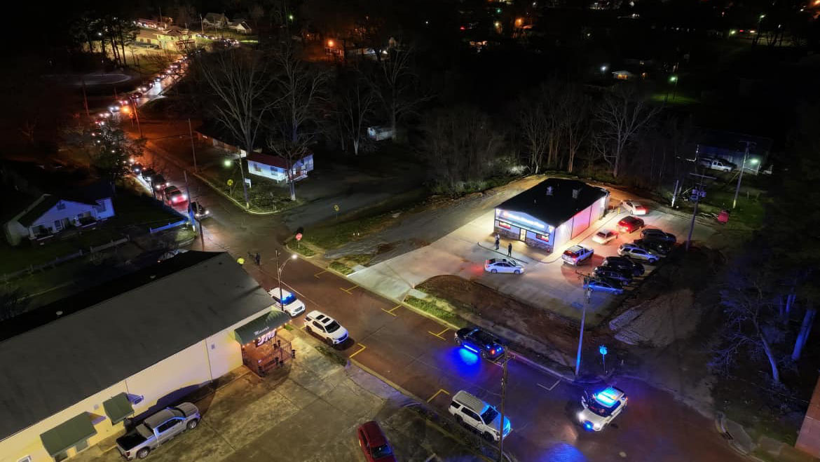 A view of an intersection at night with police cars parked on the side.