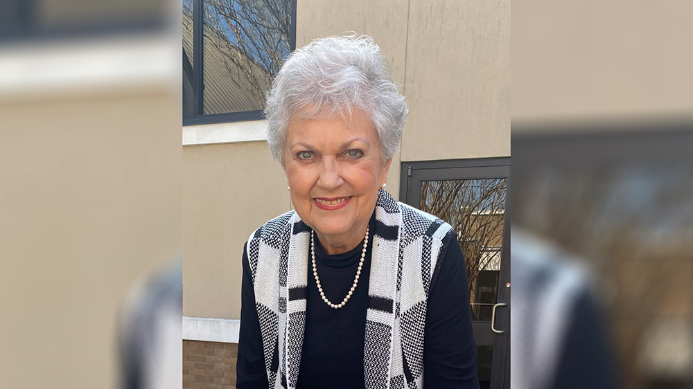 A woman with white hair wearing a black shirt and vest.