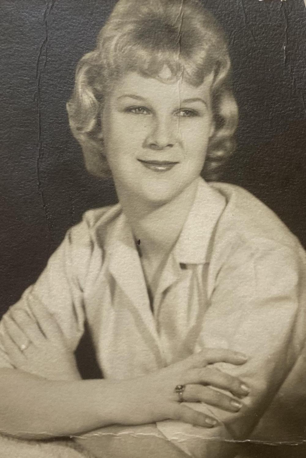A black and white photo of a woman with her arms crossed.