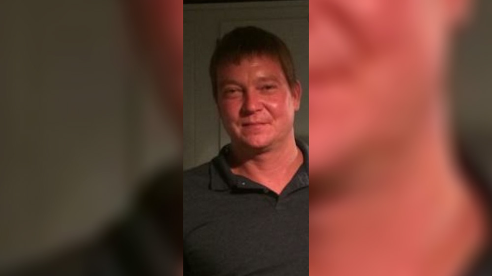 A man in a black shirt is smiling for the camera.
