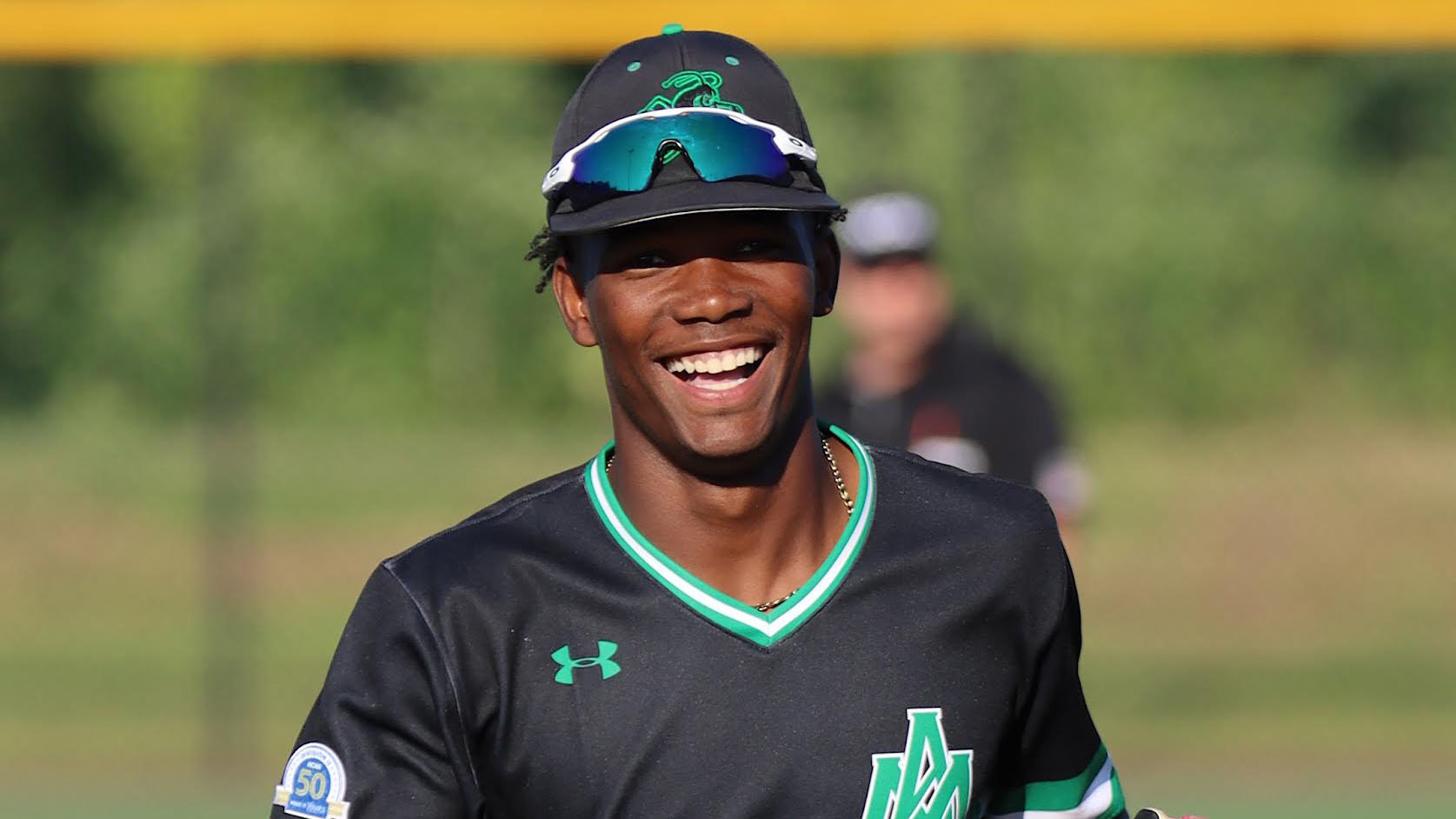 A baseball player smiles while wearing a helmet.