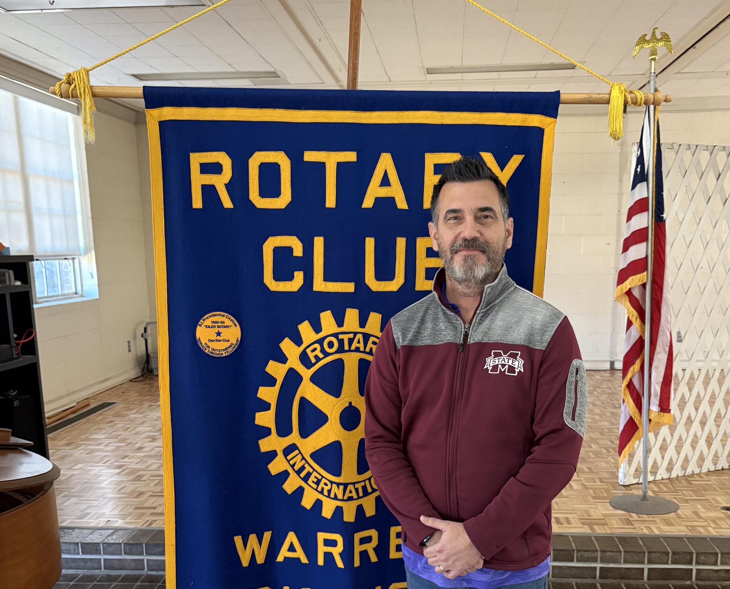 A man standing in front of a rotary club banner.