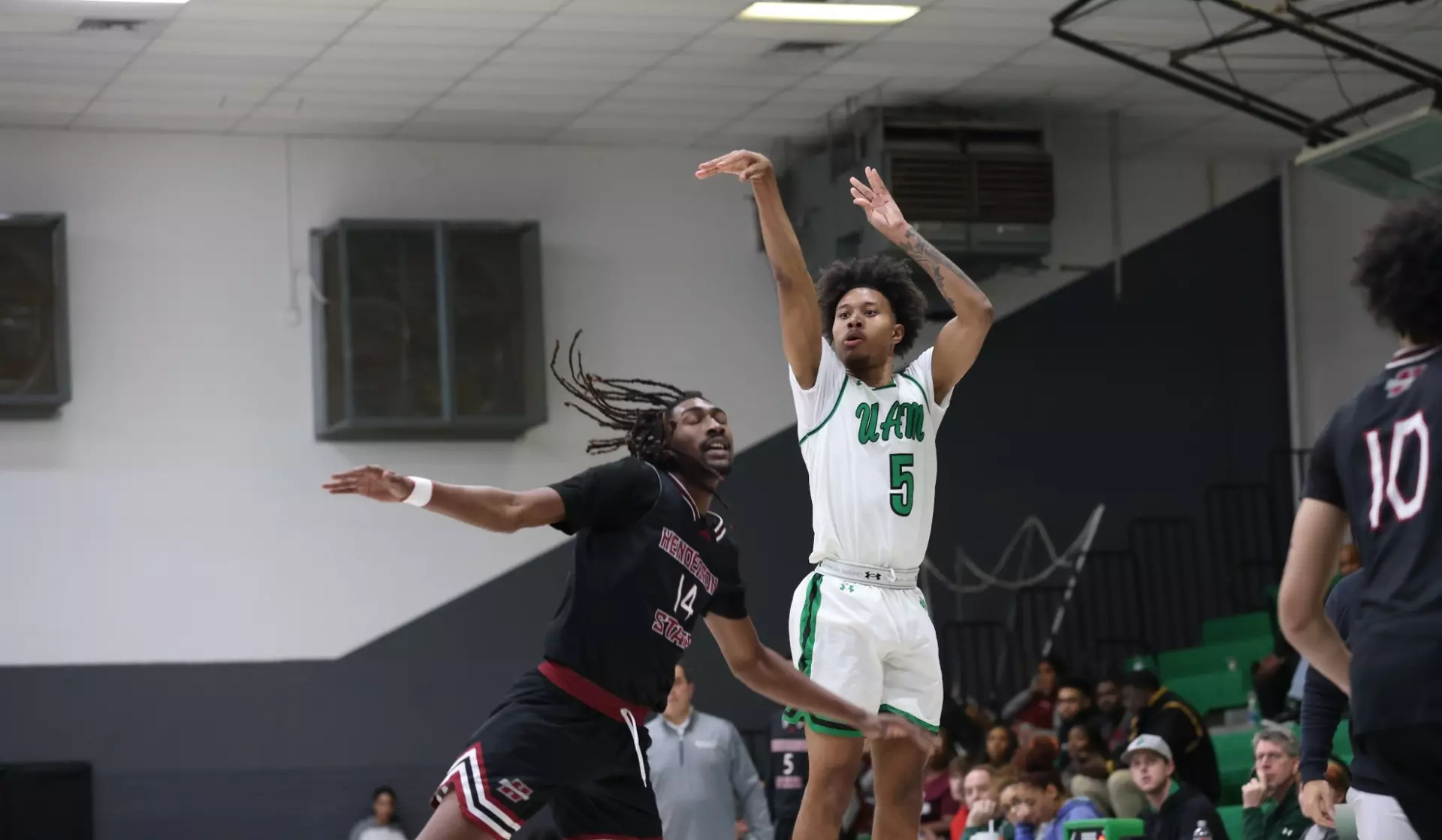 Two men playing basketball in front of a crowd.