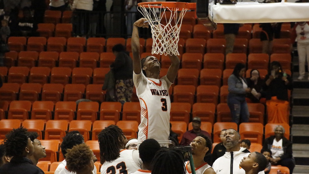 A man holding onto the rim of a basketball hoop