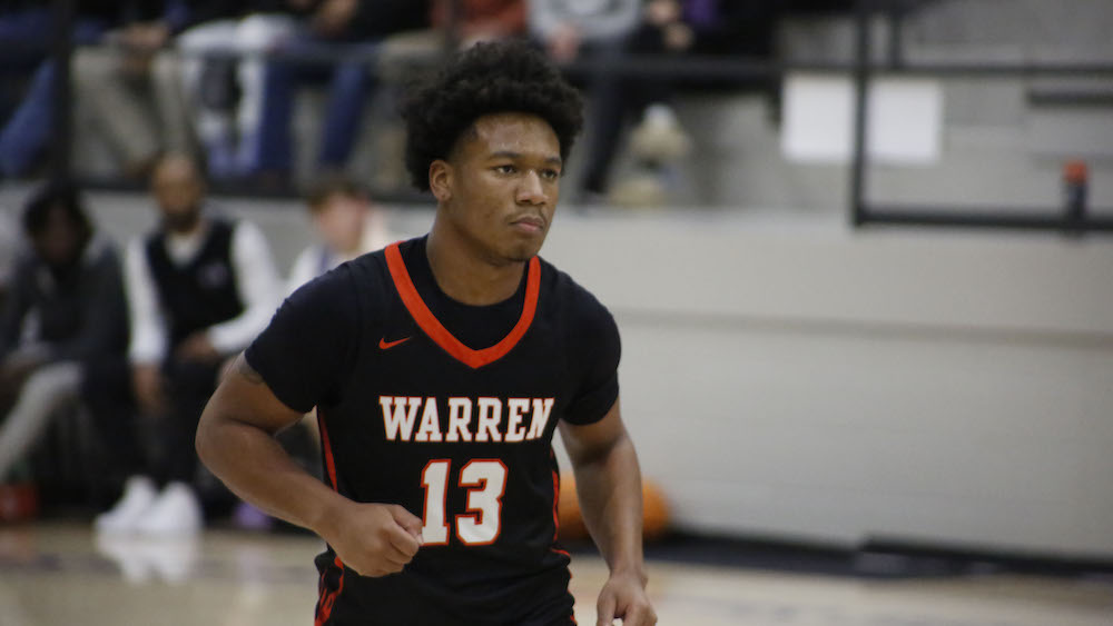 A man in black and orange shirt playing basketball.