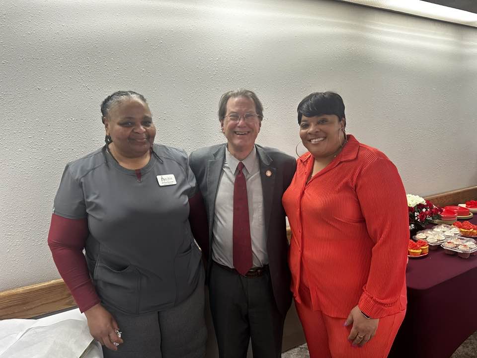 Three people posing for a picture with one man in a suit.