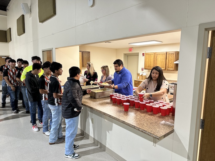 A group of people standing around a counter.