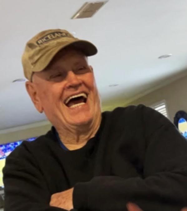 A man in a hat and glasses laughing.