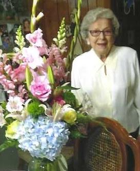 A woman standing next to a table with flowers.