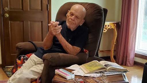 A man sitting in a chair with his hands crossed.
