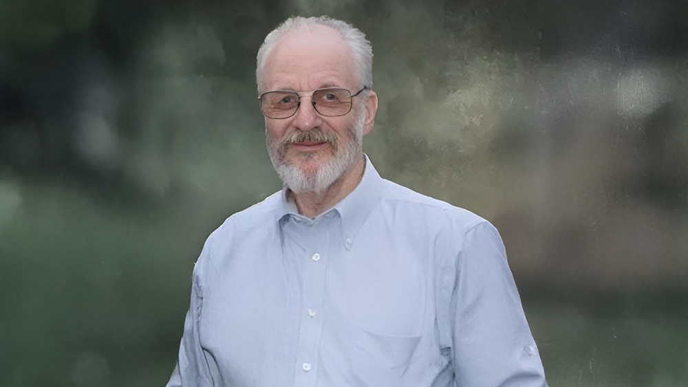 A man with glasses and beard wearing a blue shirt.
