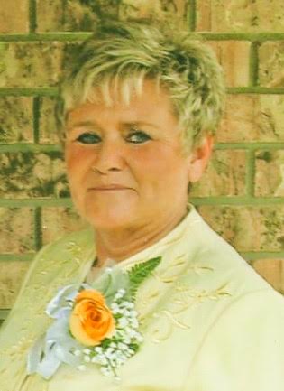 A woman with short blonde hair wearing a yellow suit.