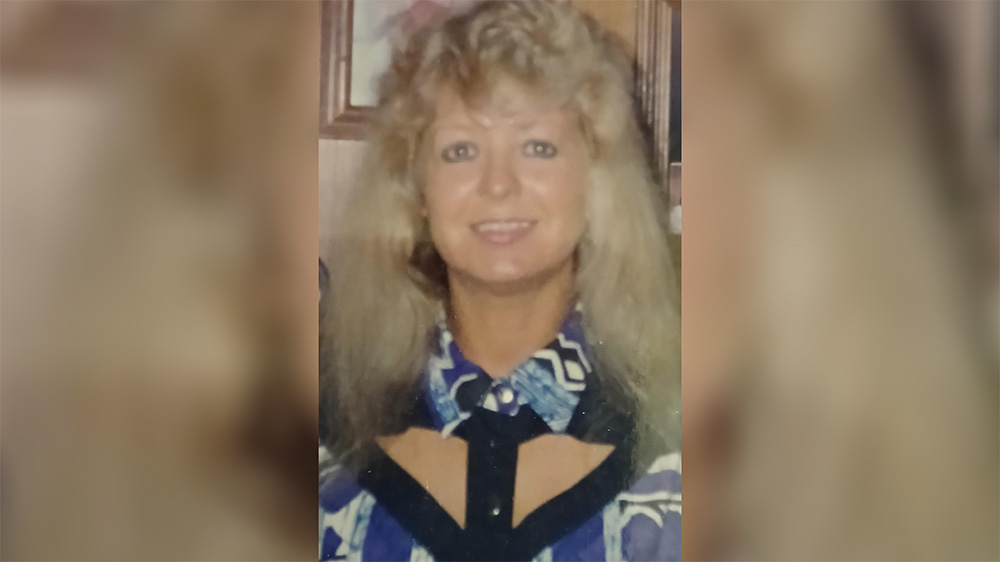 A woman with long blonde hair wearing a blue and white shirt.