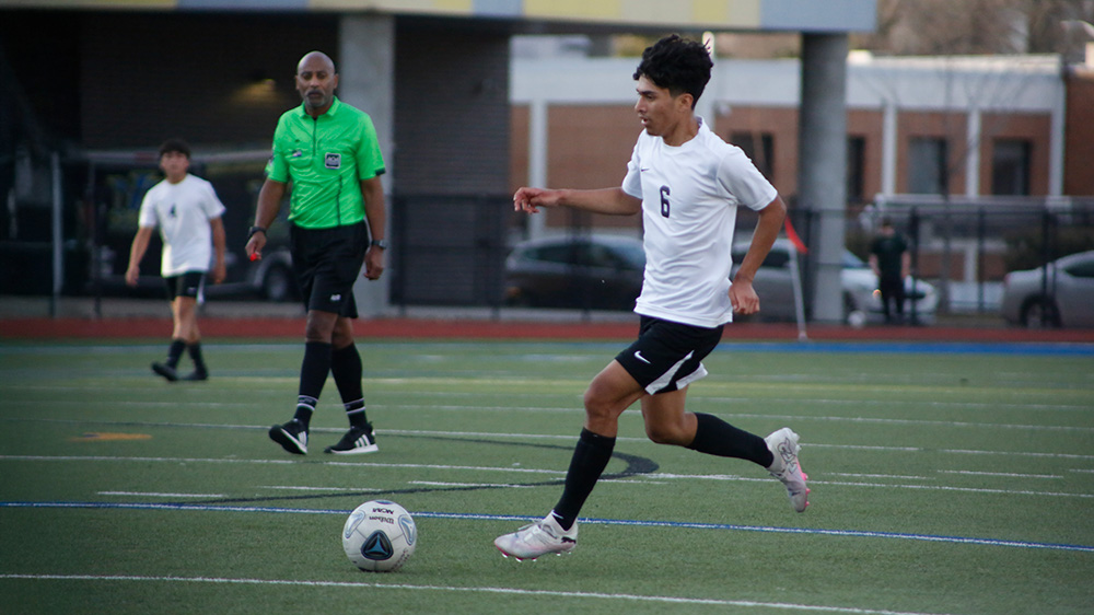 A man kicking around a soccer ball on the field.