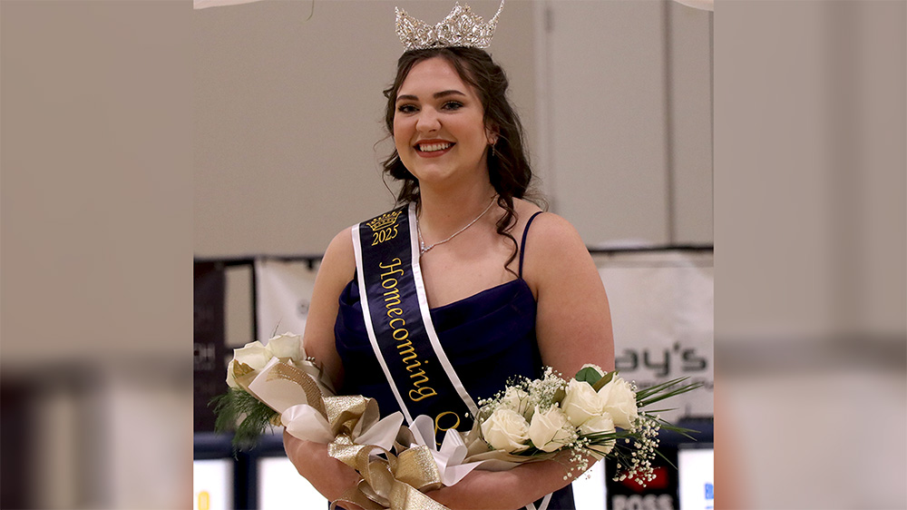 A woman in a tiara holding flowers and smiling.