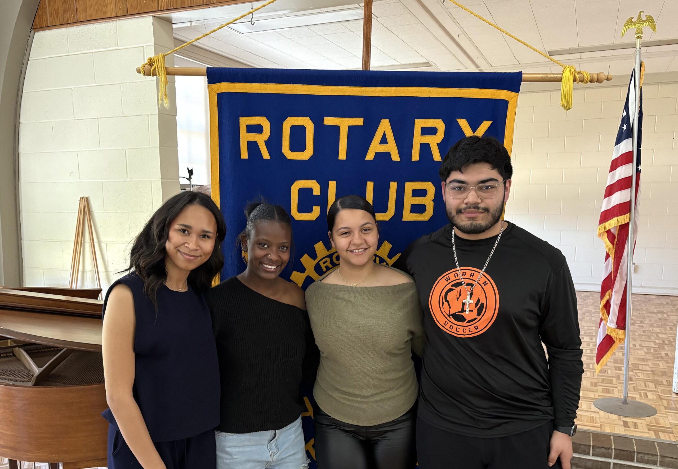 Three people standing in front of a rotary club banner.