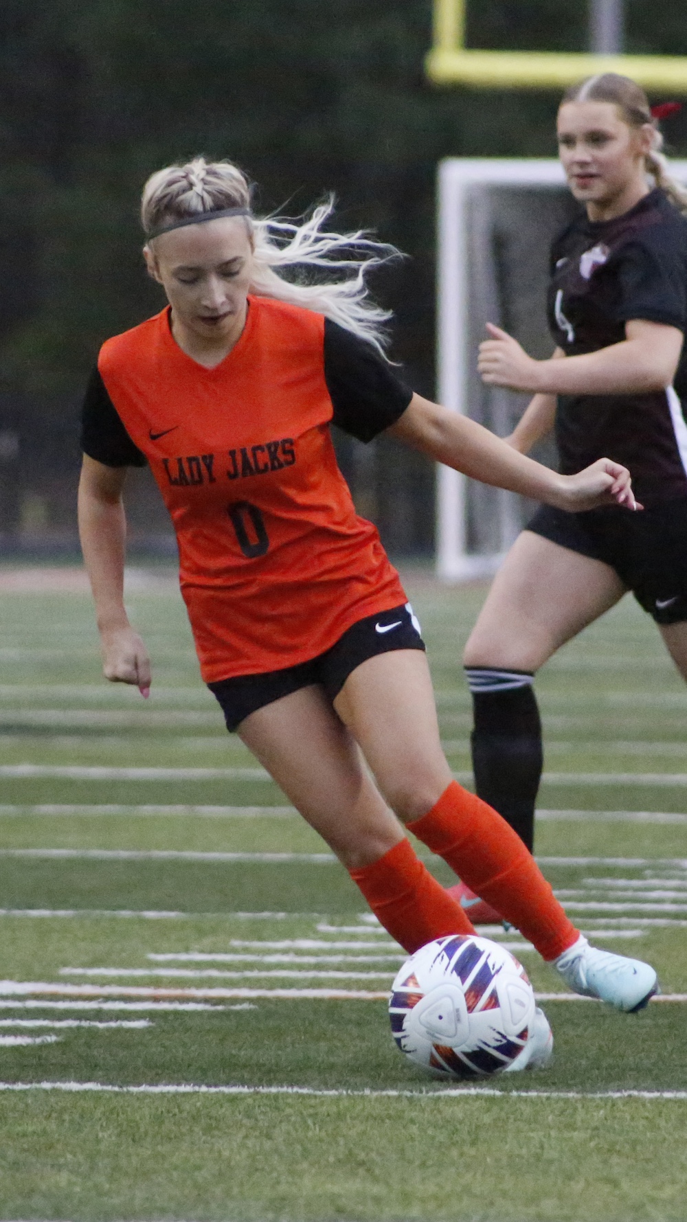 A girl in an orange shirt is playing soccer