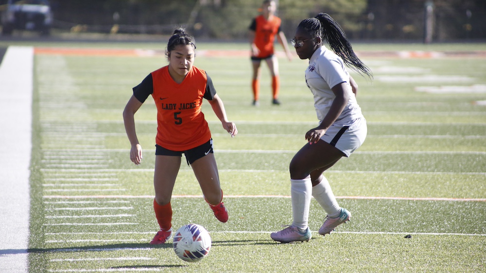 Two girls playing soccer on a field