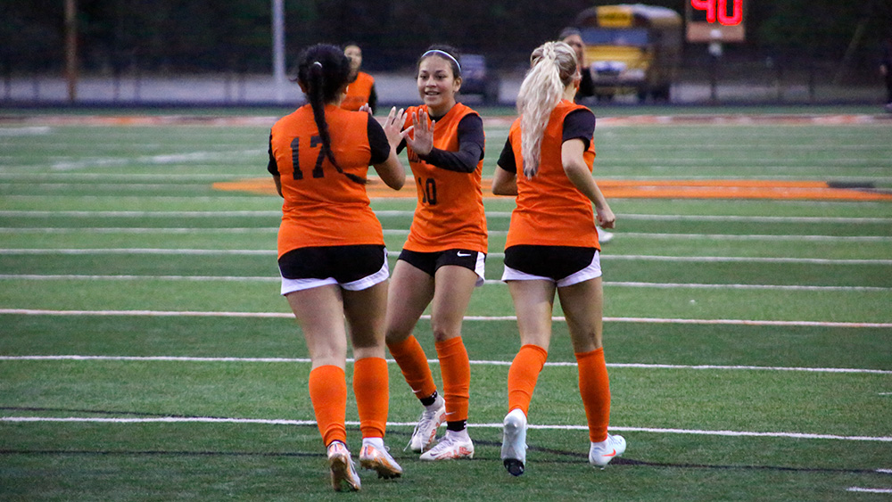 A group of women in orange and black soccer uniforms.