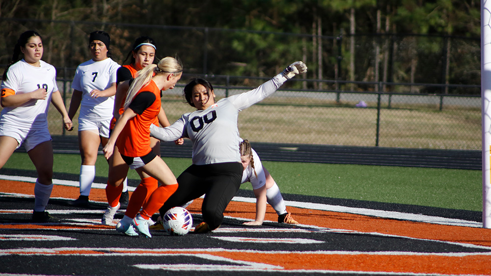 A group of girls playing soccer on the field.