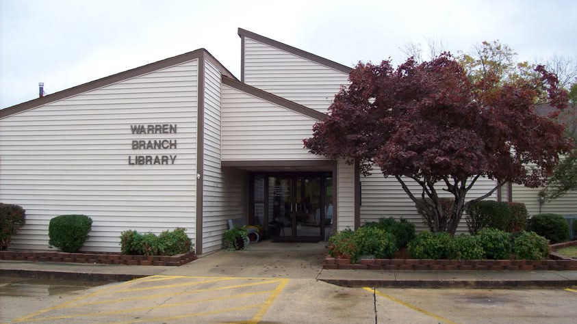A branch library building with trees in front of it.