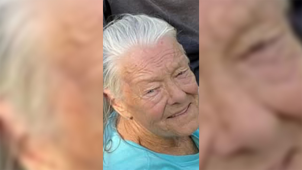 A woman with white hair and wearing glasses.
