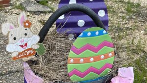 A basket with an egg on it sitting in the grass.